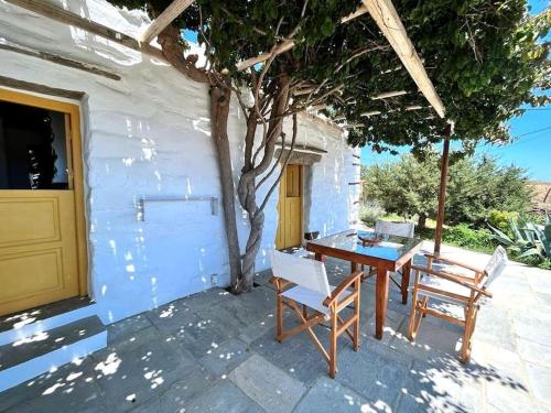 a patio with a table and chairs and a tree at Juniper Cycladic House, Serenity Sifnos in Apollonia