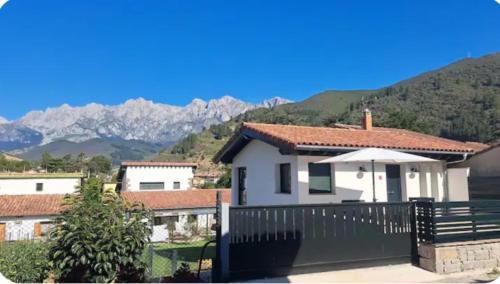 a house with a fence and mountains in the background at Mirando a los Picos de Europa in Potes