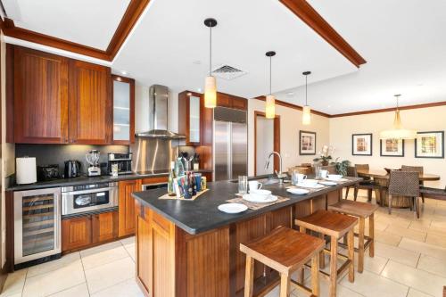 a kitchen with wooden cabinets and a kitchen island with chairs at KBM Resorts FREE CAR Beach Villas at Ko Olina BVK-B-308 Beachfront Villa in Kapolei
