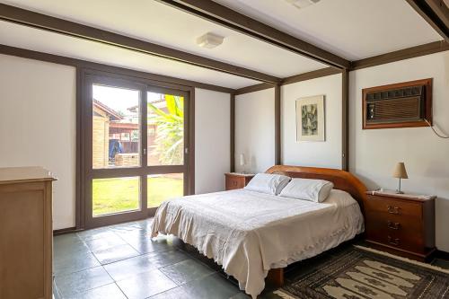a bedroom with a bed and a large window at Casa na Marina com piscina churrasqueira e píer in Guarujá