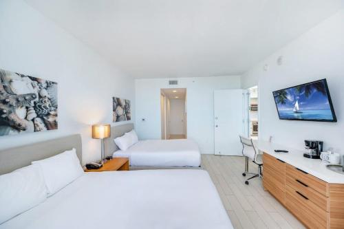 Una habitación de hotel con una cama y un escritorio con una computadora. en Amazing Family Studio at Beachwalk on Hallandale, en Hallandale Beach