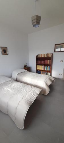 two white beds in a room with a book shelf at La Poltrona del Diavolo in Montenero