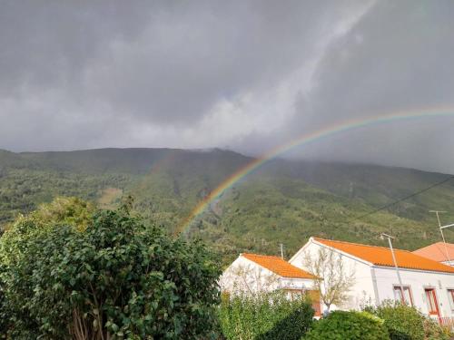 a rainbow over a house with mountains in the background at Sunflower Guest House - Madalena - Pico in São Caetano