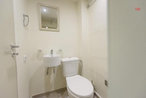 a white bathroom with a toilet and a sink at ATHENS COMMERCIAL in Athens