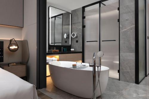 a bathroom with a bath tub and a bedroom at Crowne Plaza Taizhou City Center by IHG in Taizhou