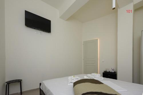 a white room with a bed and a flat screen tv at ATHENS COMMERCIAL in Athens