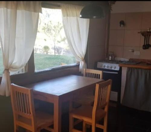 a table and chairs in a kitchen with a window at Cabañas SurEnya in El Bolsón