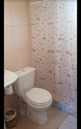 a bathroom with a toilet with writing on the shower curtain at Cabañas SurEnya in El Bolsón