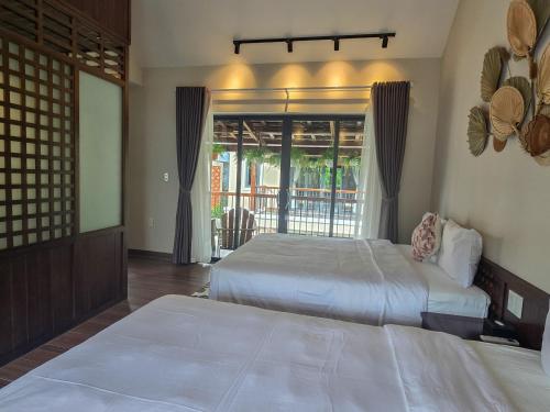 a bedroom with two beds and a large window at Sealight Villa and House Phu Quoc in Phu Quoc