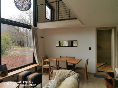 a dining room with a table and a large window at Emai in Las Trancas