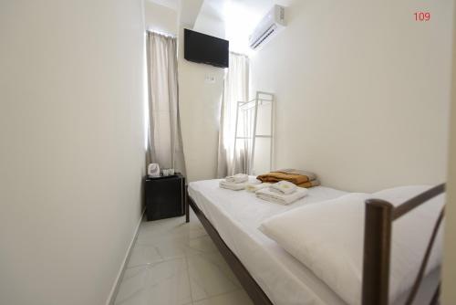 a bedroom with a bed with white sheets and towels at ATHENS COMMERCIAL in Athens
