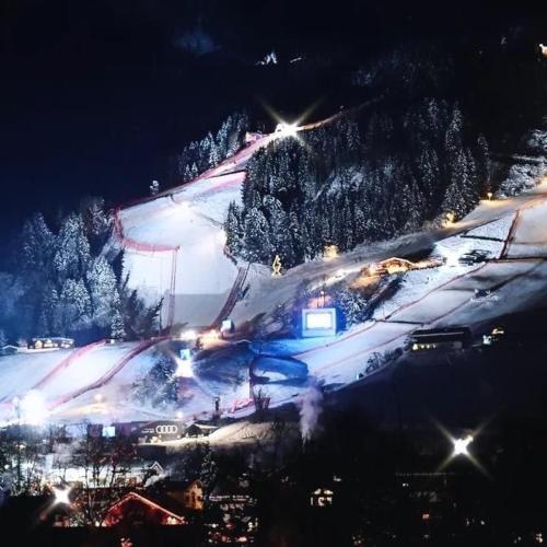 a ski slope with snow and trees at night at Hocheckhuette On Top of the Kitzbuehel Hahnenkamm Mountain in Kitzbühel