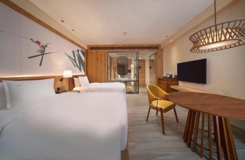 a hotel room with a bed and a table and a tv at Holiday Inn Jilin Beidahu by IHG in Jilin