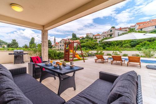a patio with a couch and a table and a playground at House Villa Gold in Splitska
