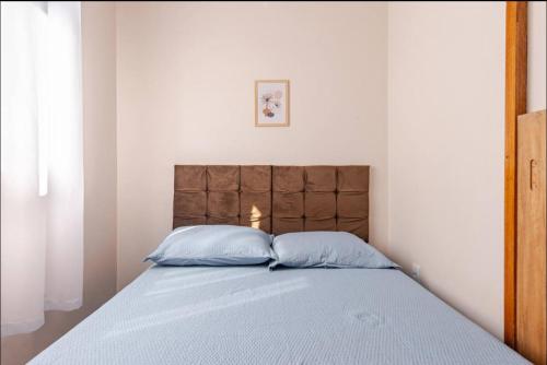 a bed with two blue pillows in a bedroom at Espaço de festas e Hospedagem Cintia Lima in Betim