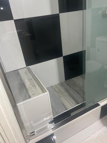 a glass shower in a bathroom with black and white tiles at New Kingston Gem in Kingston