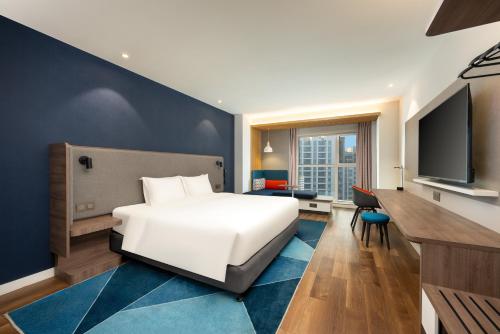 a bedroom with a white bed and a flat screen tv at Holiday Inn Express Tianjin Airport East by IHG in Tianjin