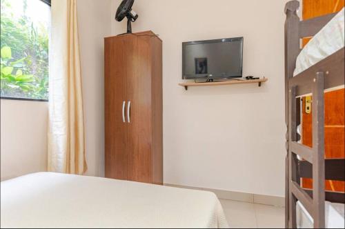 a bedroom with a bed and a tv and a cabinet at Espaço de festas e Hospedagem Cintia Lima in Betim