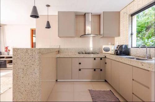 a kitchen with white cabinets and a sink at Espaço de festas e Hospedagem Cintia Lima in Betim