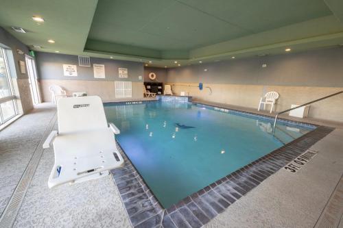 a large swimming pool with a chair next to it at Holiday Inn Express & Suites Dallas NE Arboretum in Dallas