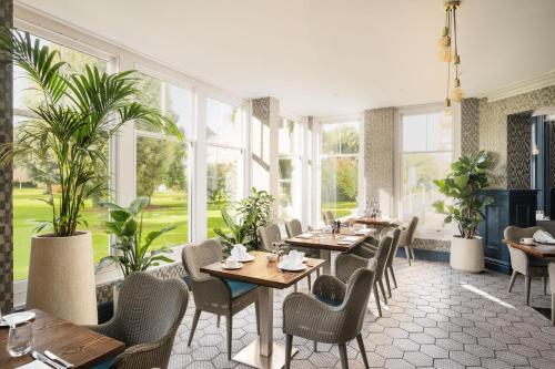 a restaurant with tables and chairs and windows at voco The Clifton Folkestone by IHG in Folkestone