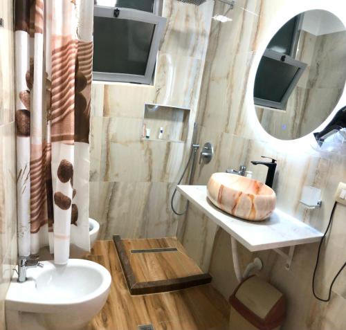 a bathroom with a sink and a toilet and a mirror at Beach Apartments Durres in Durrës