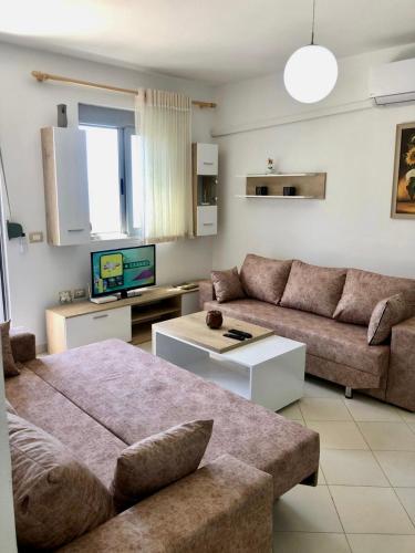 a living room with a couch and a tv at Beach Apartments Durres in Durrës