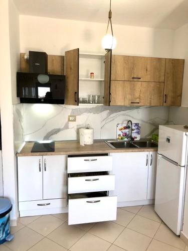 a kitchen with white cabinets and a white refrigerator at Beach Apartments Durres in Durrës
