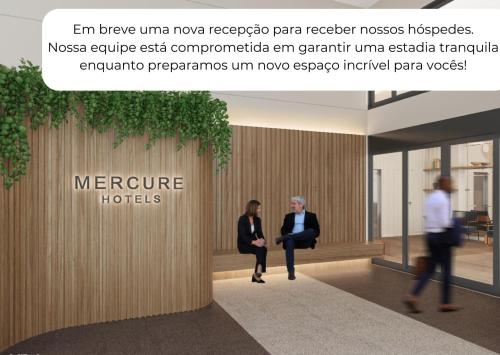 two people walking in a lobby with a sign that reads incentive hotels at Mercure Sao Paulo Moema Times Square in Sao Paulo