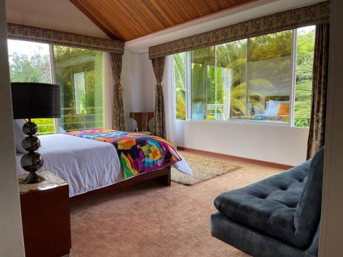 a bedroom with a bed and a couch and windows at Casa de estancia y descanso VILLA ALEJITA in Santa Rosa de Viterbo