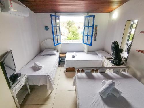 una stanza con tre letti e una finestra di Casa 12 Búzios Vilas a 500m da Rua das Pedras, top localização em condomínio lindo e calmo, portaria 24h a Búzios