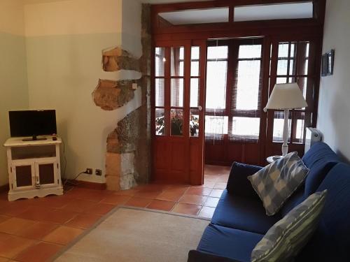 a living room with a blue couch and a tv at Finca Artienza in Ramales de la Victoria