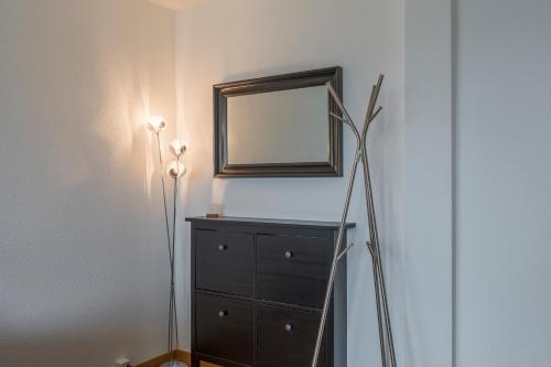 a bedroom with a dresser and a mirror on a wall at Amanthos Living Solothurn in Grenchen