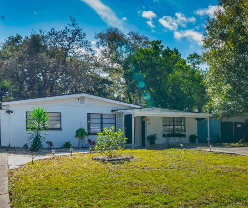 a white house with a green yard at Cozy apartment near Busch Gardens Adventure Island and USF in Tampa