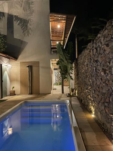 a swimming pool in a house with a stone wall at Gostoso Maresia Flats in São Miguel do Gostoso