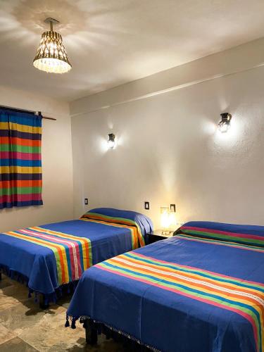 a bedroom with two beds with colorful blankets at Hotel Yalnazac Mitla in San Pablo Villa de Mitla