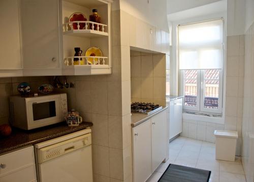 a kitchen with white cabinets and a microwave at Chiado Lisbon Apartment in Lisbon
