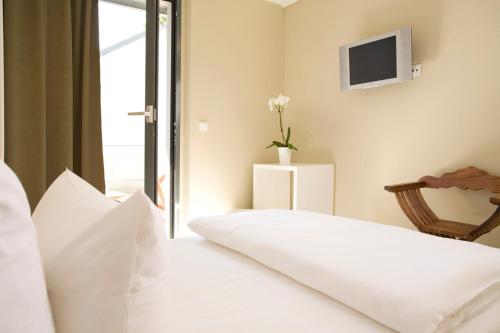 a bedroom with a white bed with a tv on the wall at Pension Mariposa in Weimar