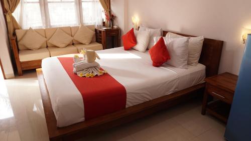 a bedroom with a large bed with red and white pillows at Grand Raka Homestay in Lovina