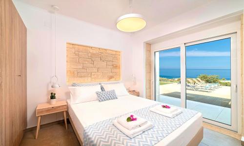 a bedroom with a bed with a view of the ocean at Vista Mare Maxima Beheizter Pool in Dhrámia