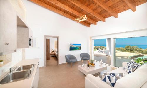 a living room with a couch and a kitchen with a view of the ocean at Vista Mare Maxima Beheizter Pool in Dhrámia