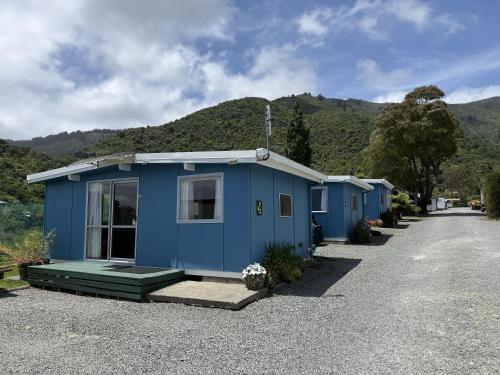 a blue tiny house with mountains in the background at Picton's Waikawa Bay Holiday Park in Picton