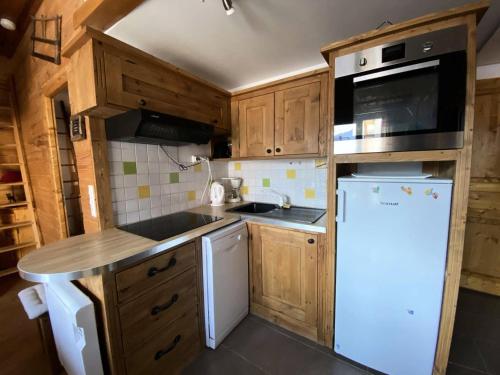 une cuisine avec des armoires en bois et un réfrigérateur blanc dans l'établissement Résidence Scrischss - T2 de 6 couchages idéalement situé au cœur de la station, avec place de parking privée couverte MAE-5001, à Vénosc