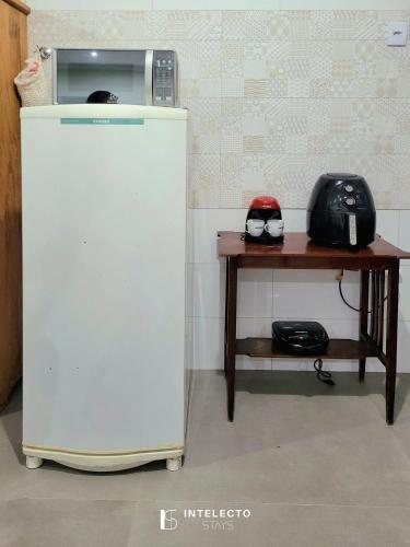 a white refrigerator next to a small table at Casa - Centro Px Matriz c/ Churrasqueira, 2 Suítes in Poços de Caldas