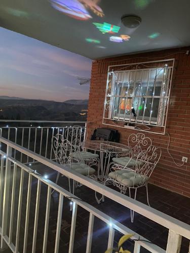 a balcony with chairs and a table and a window at Casa rural Balcón de Monachil in Monachil