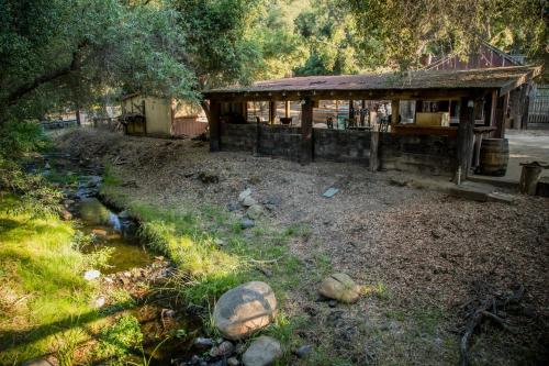 a building in a field with a creek in front at Historic Farmhouse on 5 Peaceful Acres with Ancient Oaks & Creek above Temecula in Temecula
