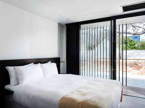 a bedroom with a white bed and a large window at The Conservatory in Hobart