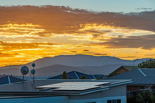 a sunset with solar panels on the roofs of buildings at Luxurious Hobart Holiday Home with Stunning Bay Views - Affordable, Family-Friendly, and Stylish in Sorell