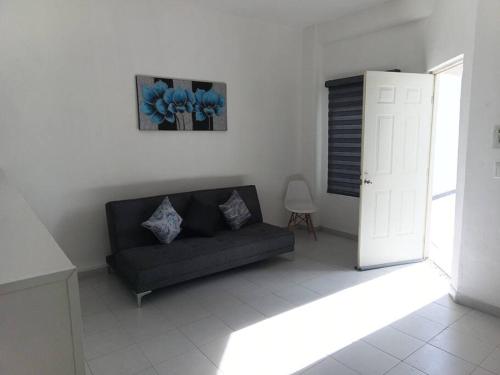 a living room with a black couch and a window at Departamento Suite in Hércules