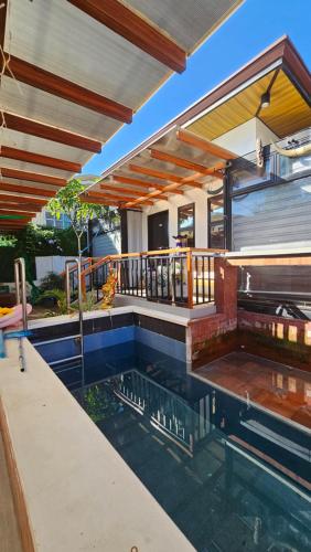a swimming pool with a patio and a house at Jolie Joes One Bedroom Unit in Tagudin